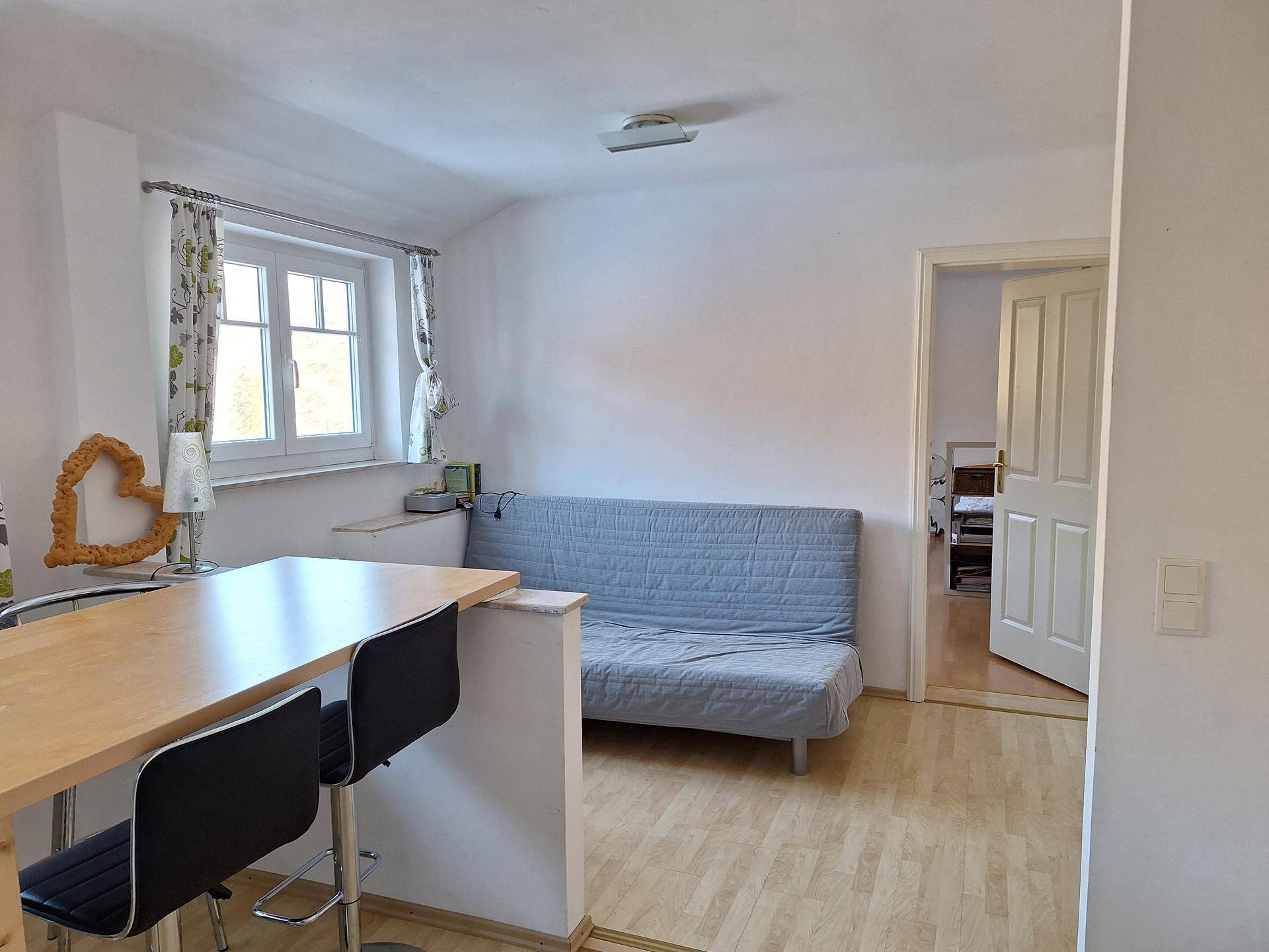 Gemütlicher Wohnbereich mit Schlafsofa, Fenster und Verbindung zur Küche.