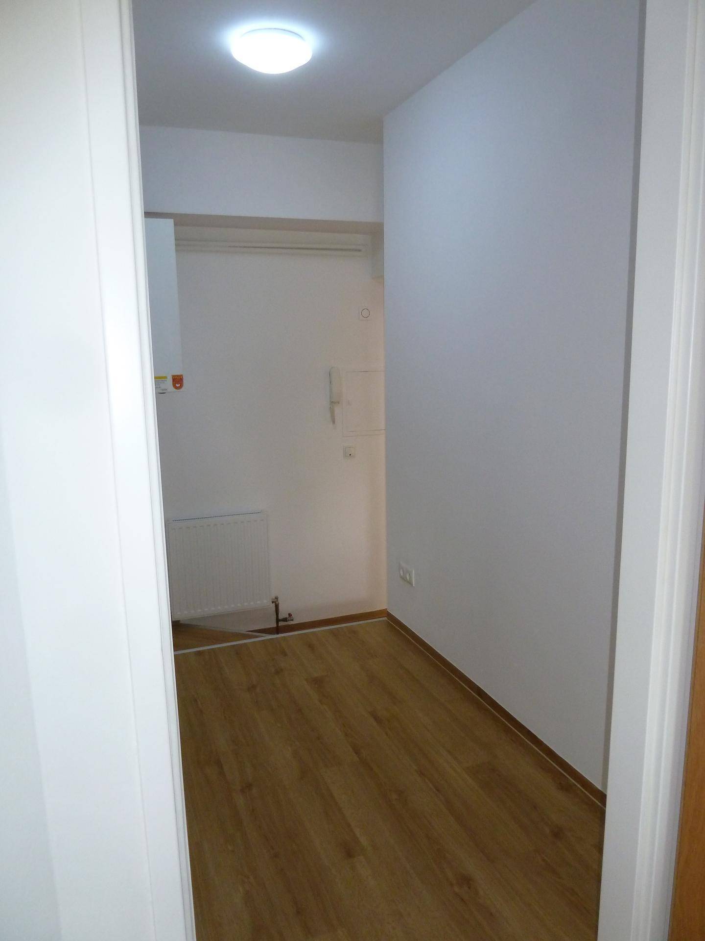 Schmaler Hauswirtschaftsraum mit Holzfußboden und Heizkörper, ideal für Lagerung.