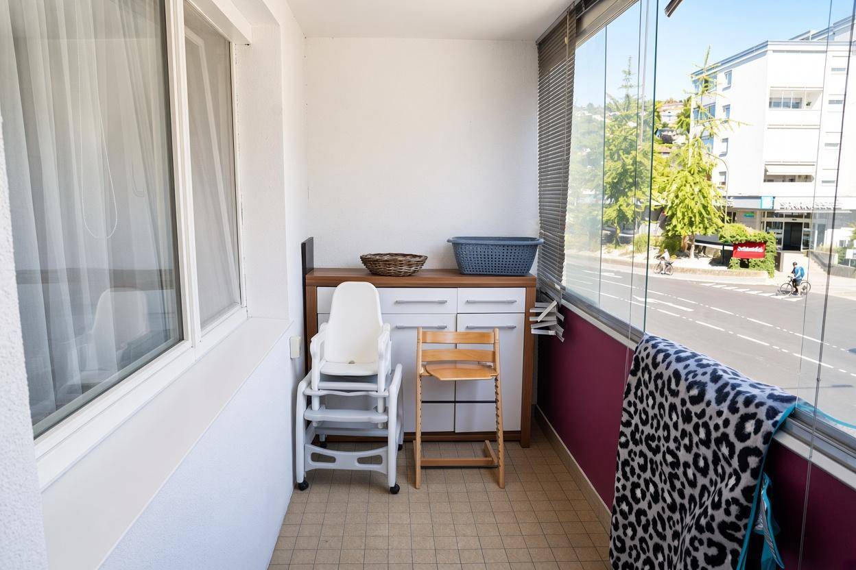 Verglaster Balkon mit Blick auf die Straße, genutzt als zusätzlicher Wohnraum.