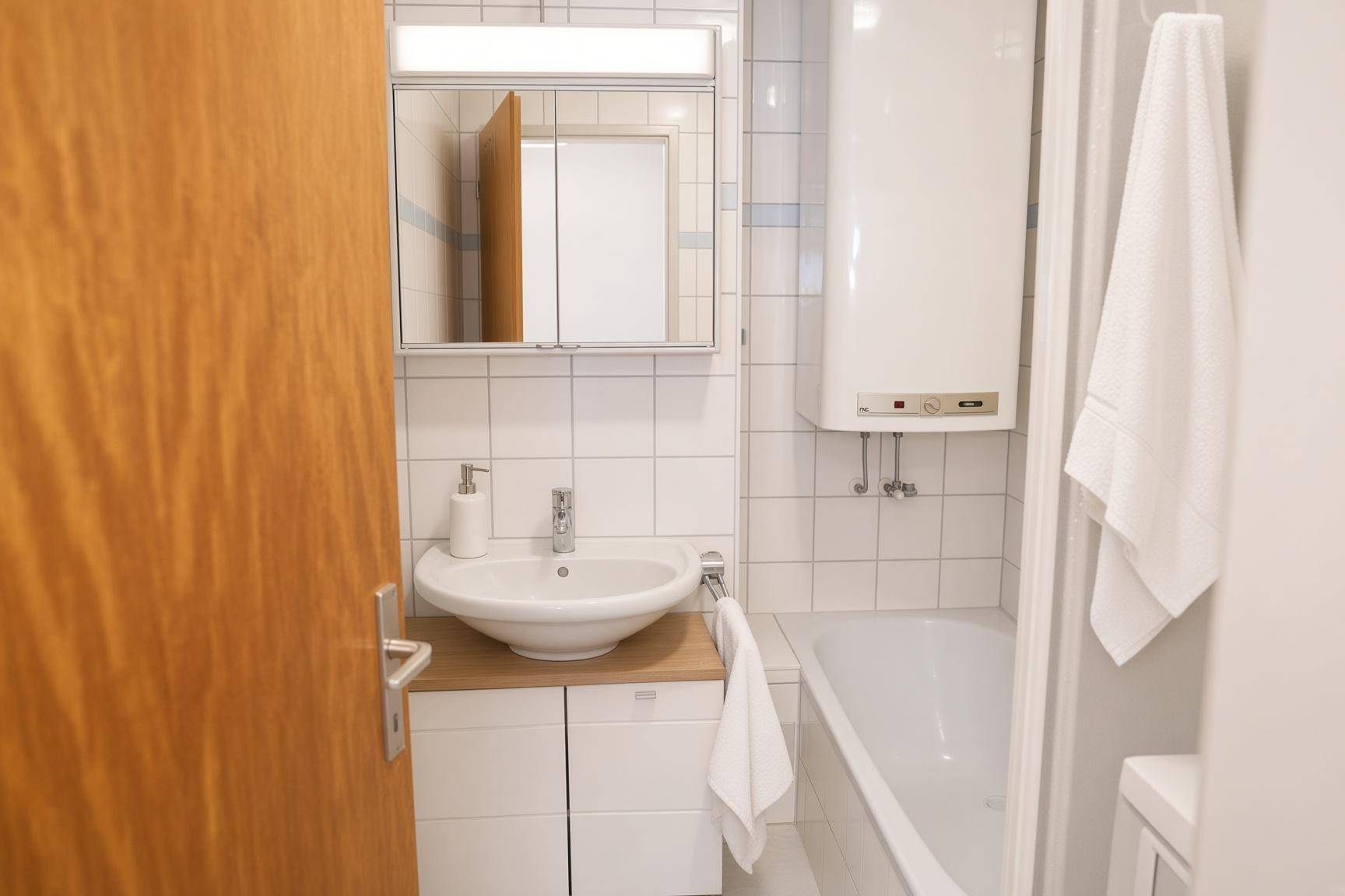 Badezimmer mit Badewanne, Waschbecken und weißen Fliesen.