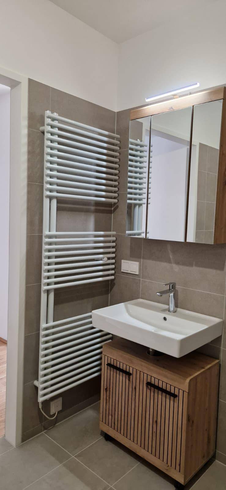 Modernes Badezimmer mit Einzelwaschbecken, Spiegelschrank und beheiztem Handtuchhalter.