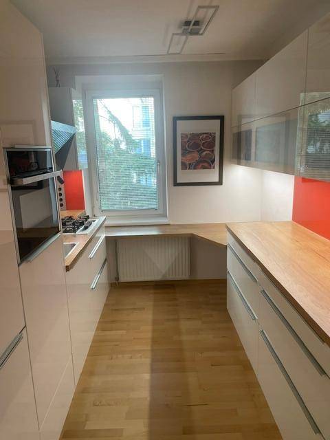 Helle, moderne Küche mit Holz-Arbeitsplatten und viel Stauraum, Blick nach draußen.