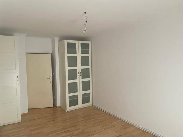 Leeres Zimmer mit Parkettboden und einem Schrank, bereit zur individuellen Gestaltung.