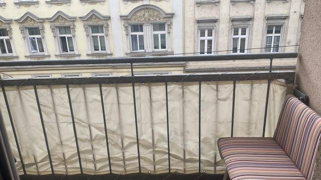 Balkon mit einfacher Sitzgelegenheit und Sichtschutz, Blick auf die gegenüberliegende Fassade.