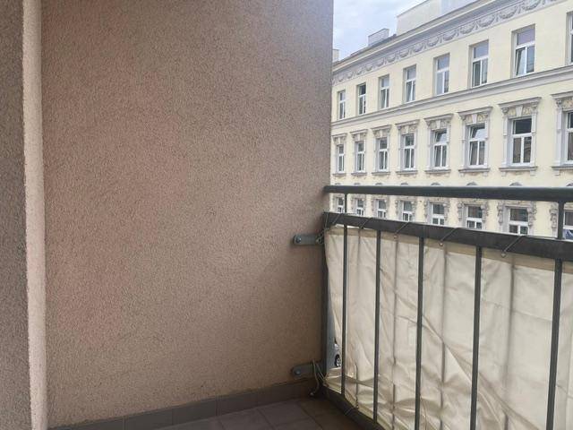 Kleiner Balkon mit Blick auf die gegenüberliegende Fassade eines Altbaus.