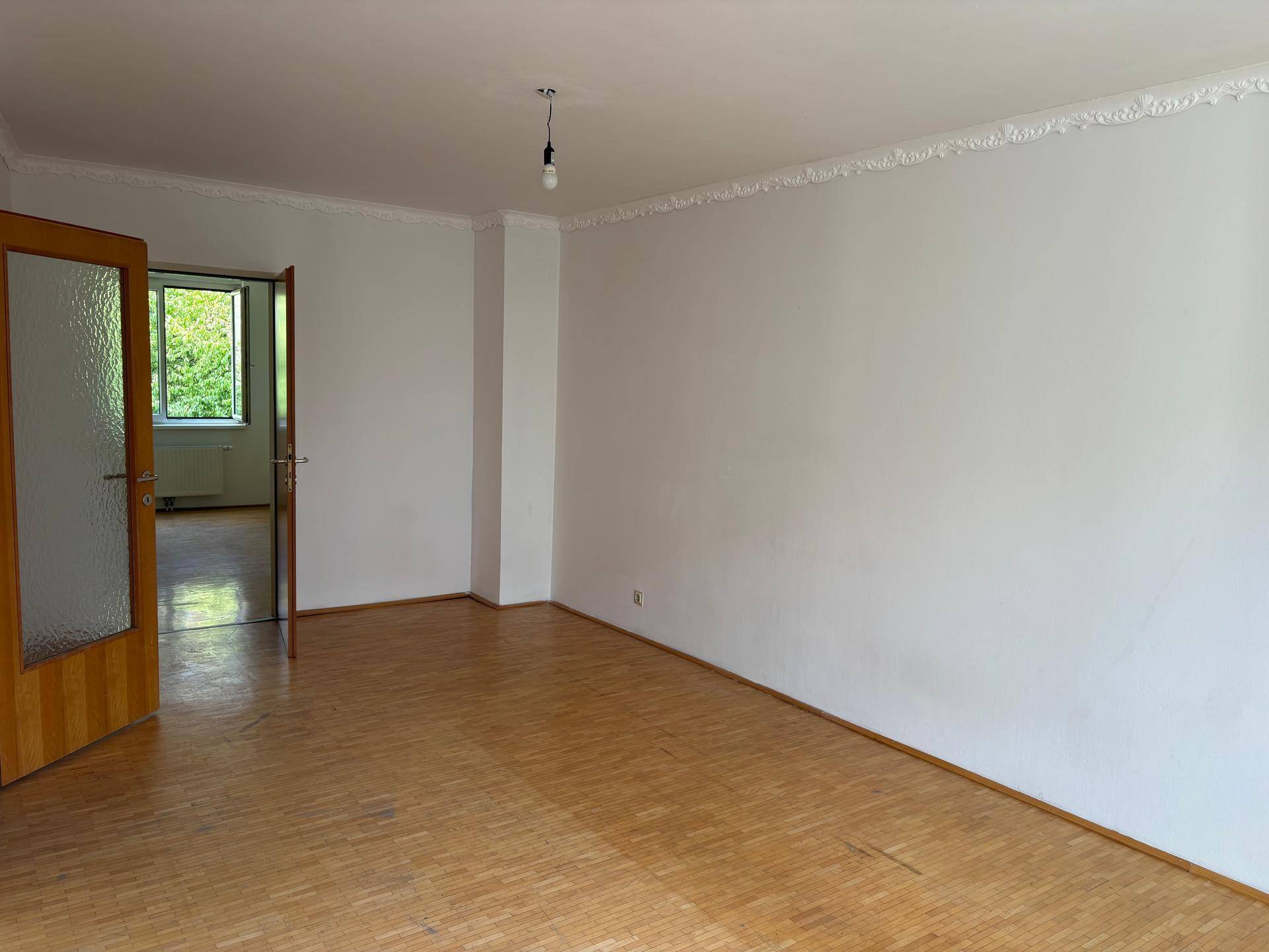Geräumiger, heller Raum mit Parkettboden und dekorativer Deckenleiste, bietet vielseitige Nutzungsmöglichkeiten.