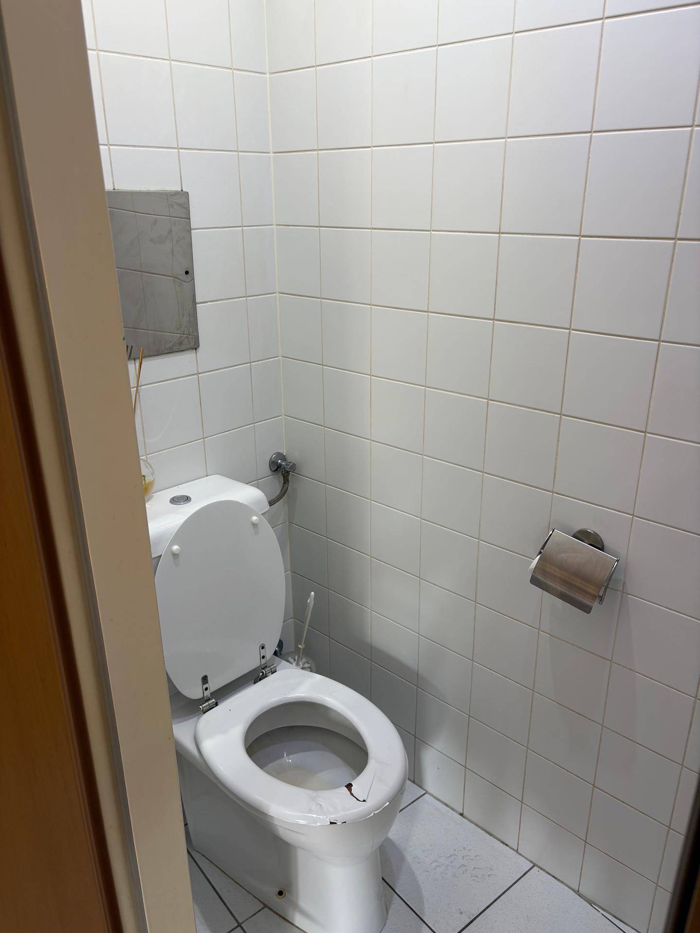 Kleines Gäste-WC mit Toilette und weißen Wandfliesen, funktional und sauber.
