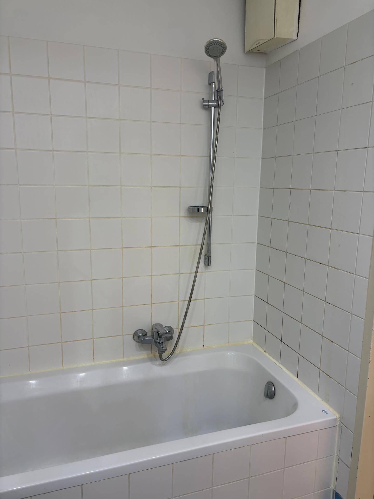 Eingebaute Badewanne mit Duschvorrichtung und weißen Fliesen, praktisch und pflegeleicht.