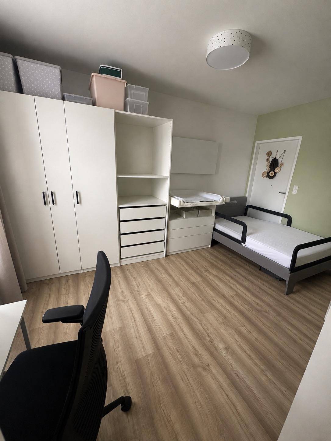 Kinderzimmer mit weißem Kleiderschrank, Wickeltisch und Laminatboden.