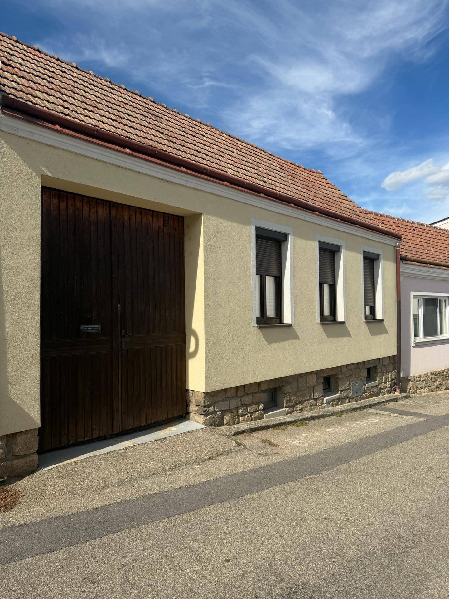 Fassade eines Wohnhauses mit großen Holztoren und Rollläden an den Fenstern.