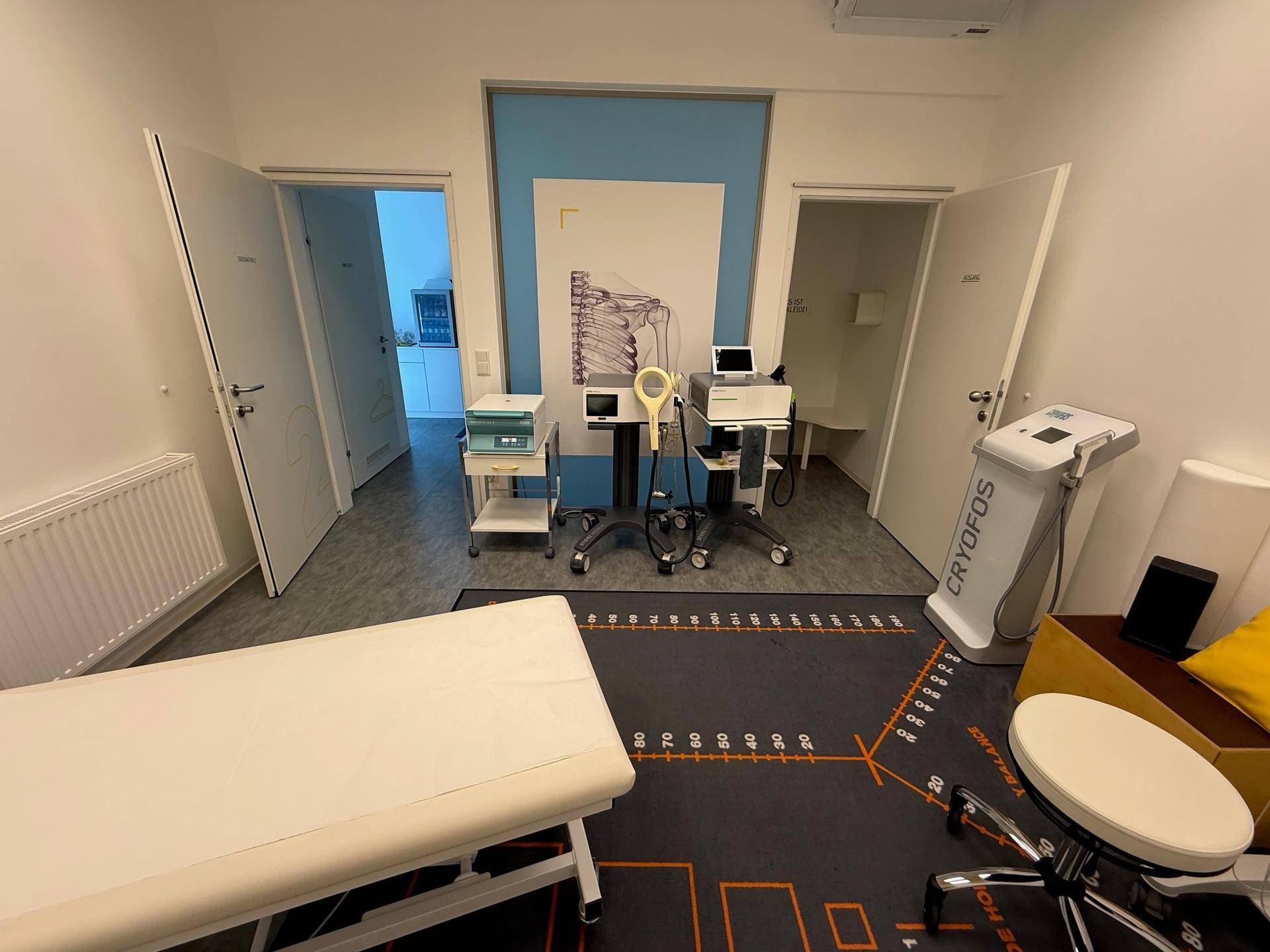 Behandlungsraum mit Liege und medizinischen Geräten, bereit für verschiedene Therapien.