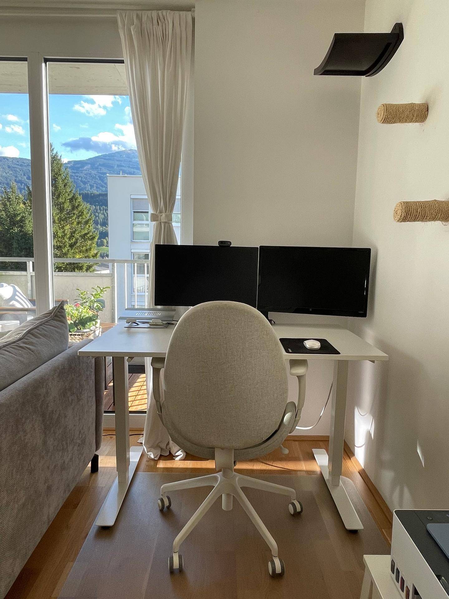 Heller Arbeitsbereich mit großem Fenster, Bergblick und Zugang zum Balkon.