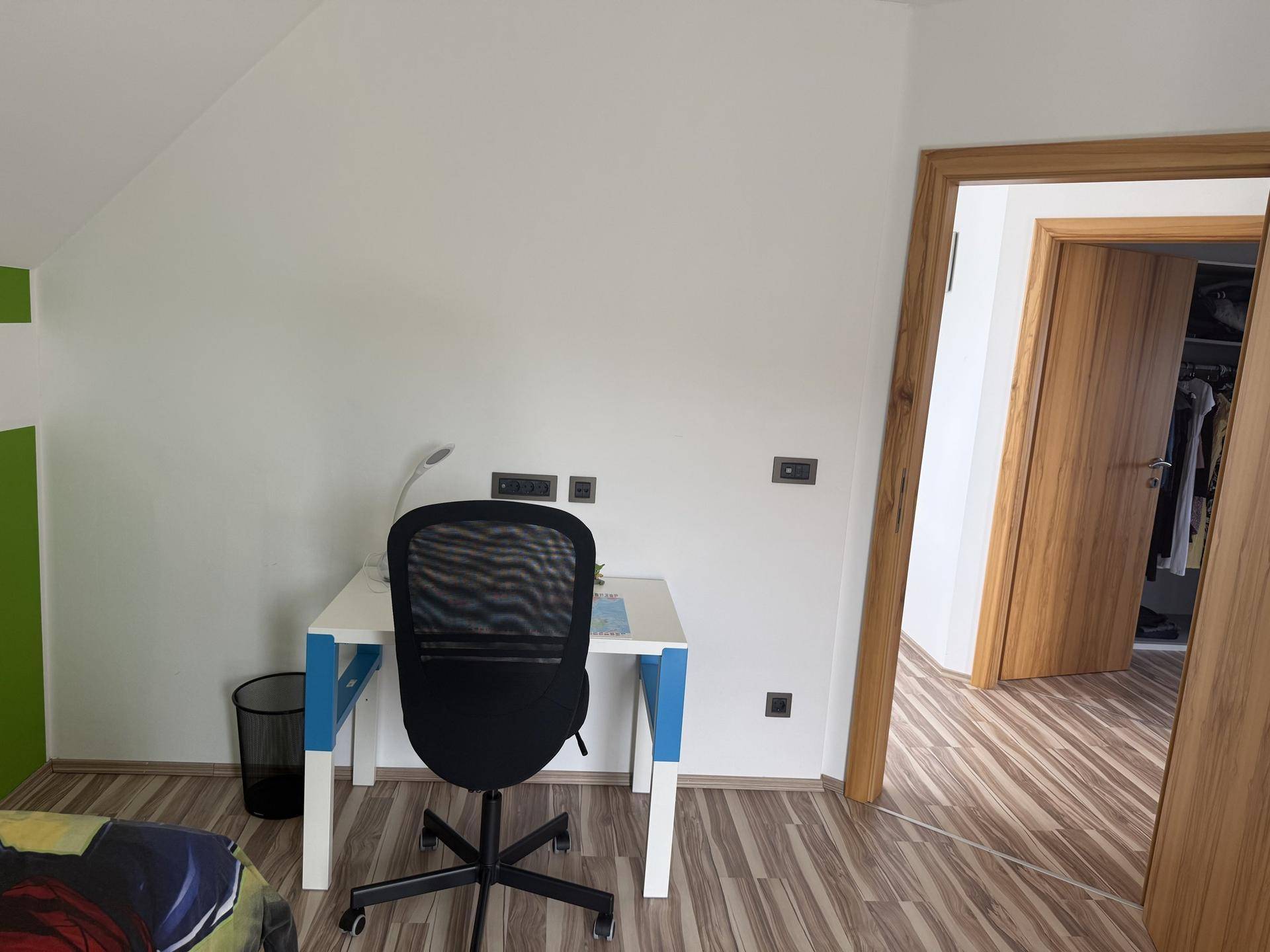 Arbeitsbereich im Schlafzimmer mit Schreibtisch, Bürostuhl und Holzboden.