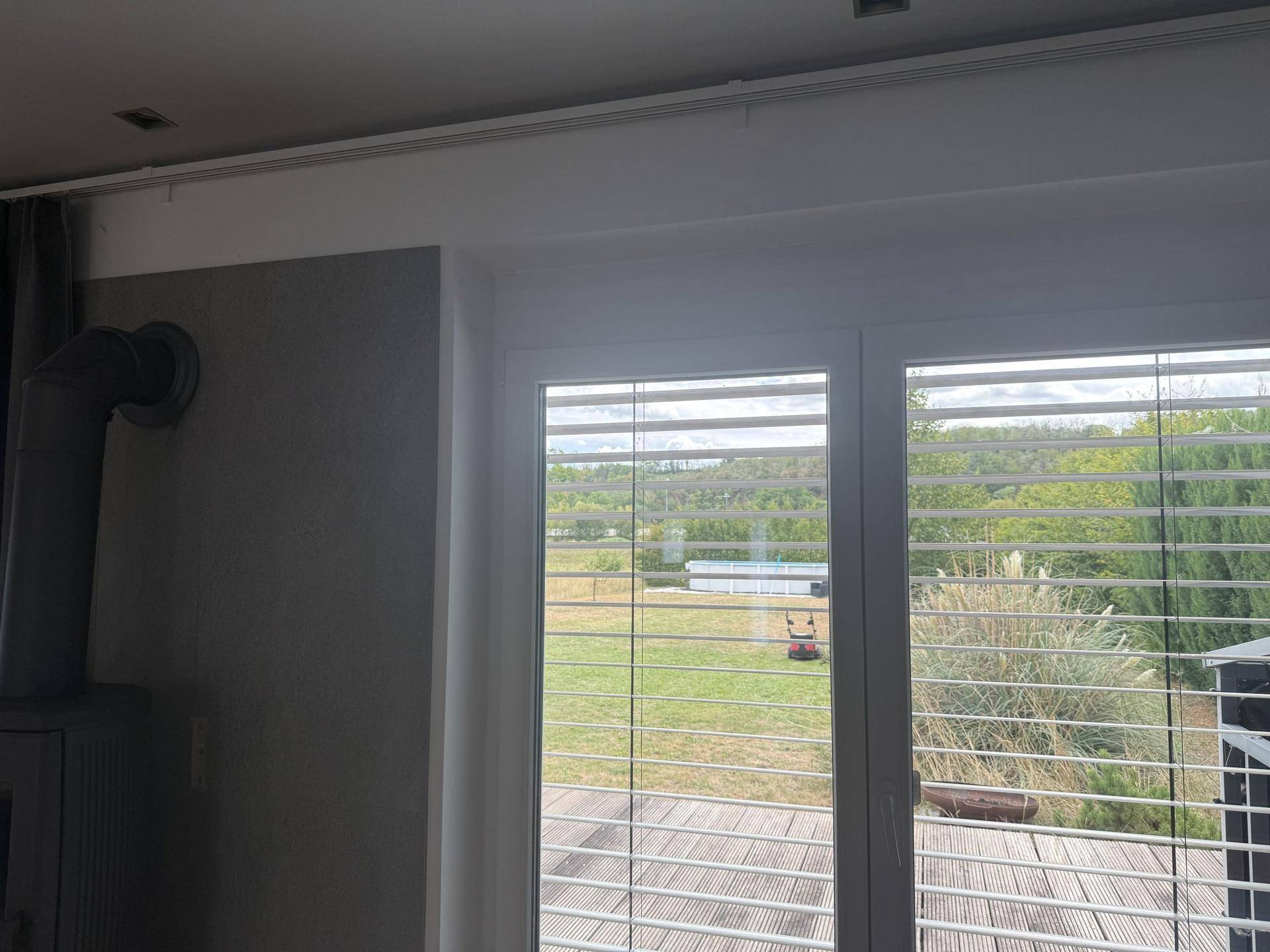Große Fenster im Wohnzimmer mit Blick auf den Garten und einen kleinen Pool.
