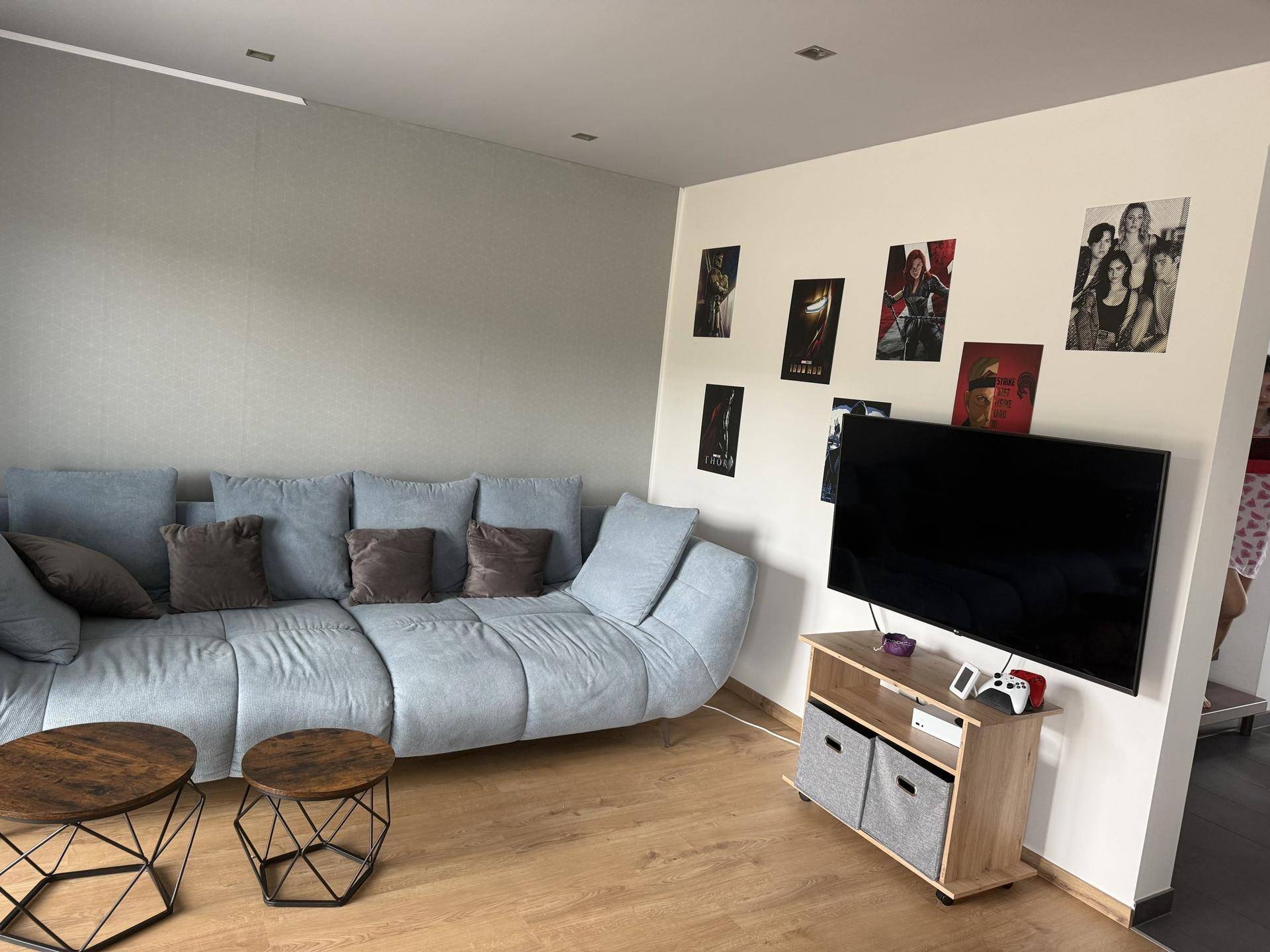 Gemütliches Wohnzimmer mit großem Sofa, Fernseher und dekorativen Bildern an der Wand.