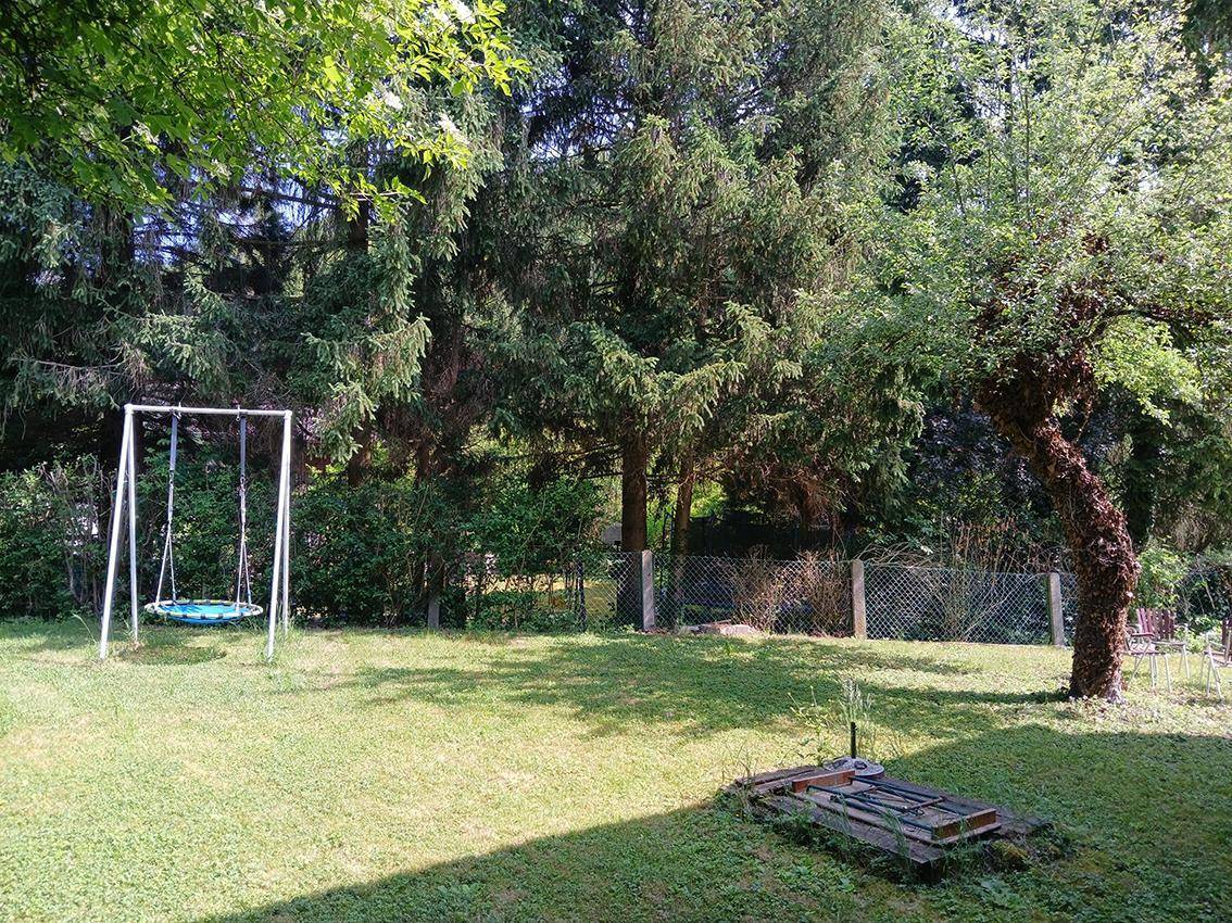 Weitläufiger Garten mit Schaukel, altem Baumbestand und viel Grünfläche.