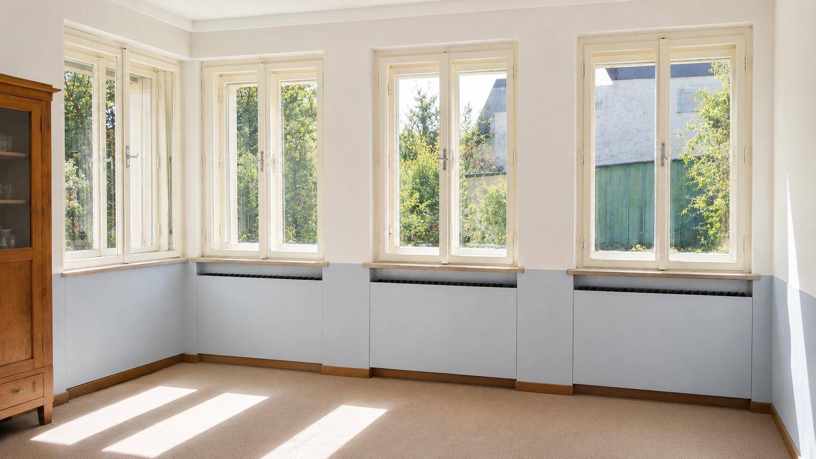Heller Raum mit Teppichboden, hellblauen Wänden und vielen Fenstern für natürliche Beleuchtung.