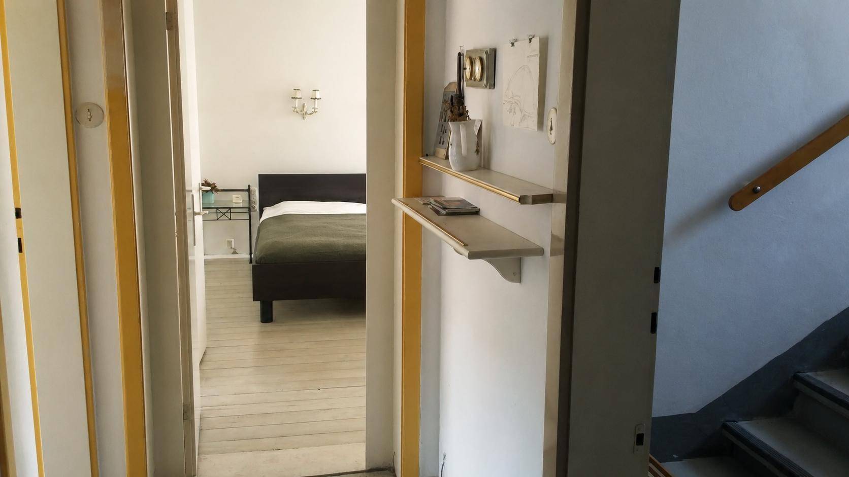 Heller Flur mit Regalen und Zugang zu einem Schlafzimmer, Treppe sichtbar.