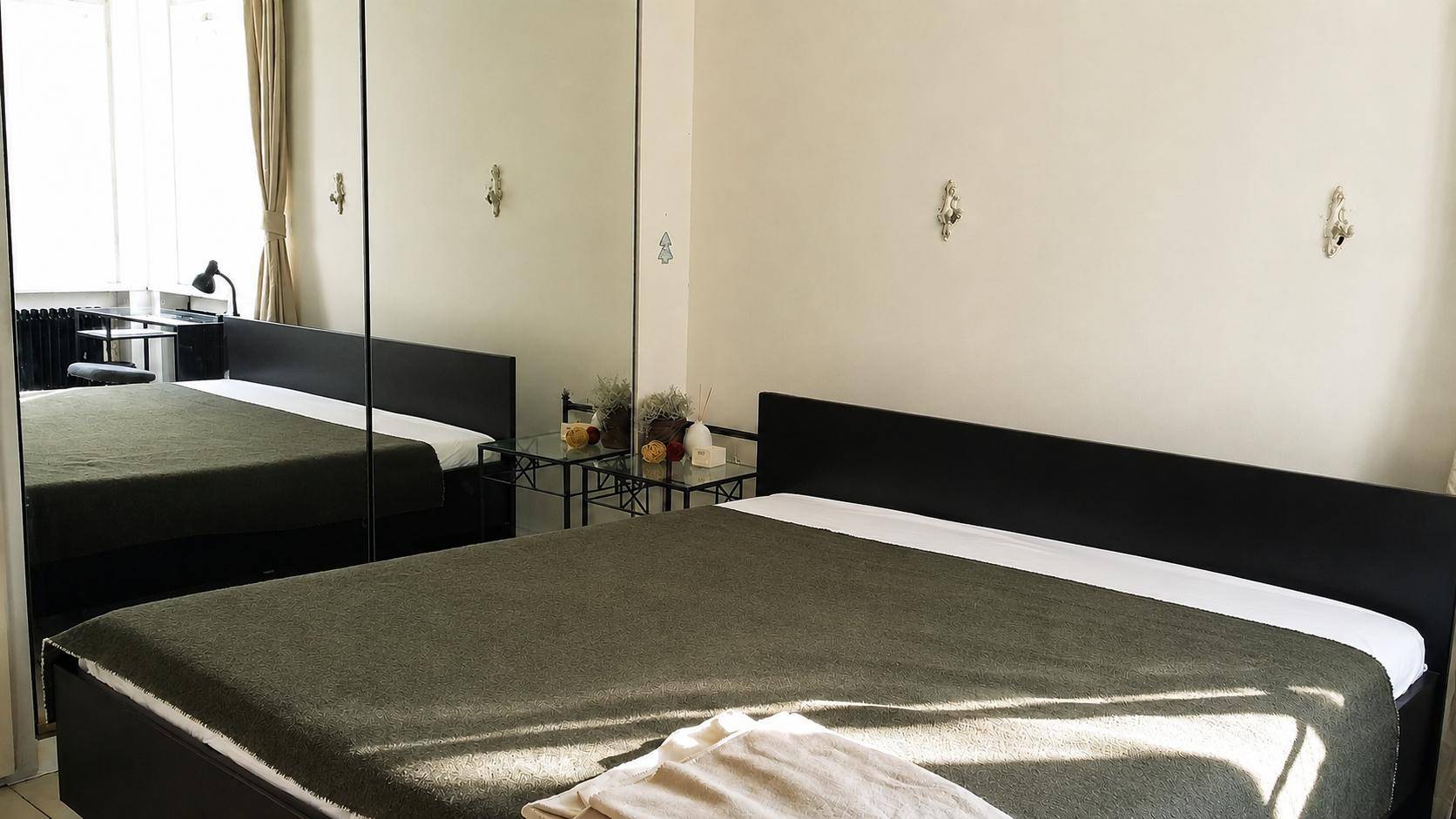 Schlafzimmer mit Doppelbett und großem Spiegelschrank, der den Raum optisch vergrößert.