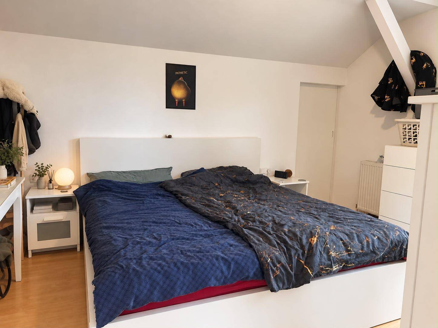Gemütliches Schlafzimmer mit großem Bett, Nachttischen und schrägen Decken im Dachgeschoss.