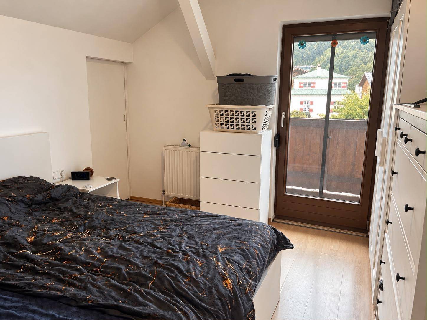 Schlafzimmer mit Doppelbett, Kommode und direktem Zugang zu einem Balkon mit Bergblick.