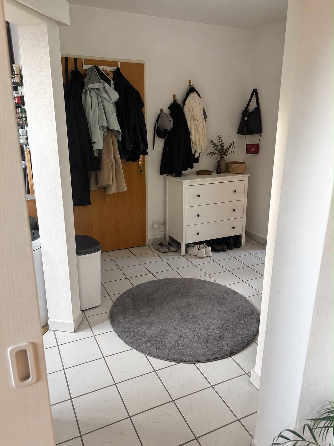 Heller Eingangsbereich mit Fliesenboden, Garderobe und einer Kommode für Stauraum.