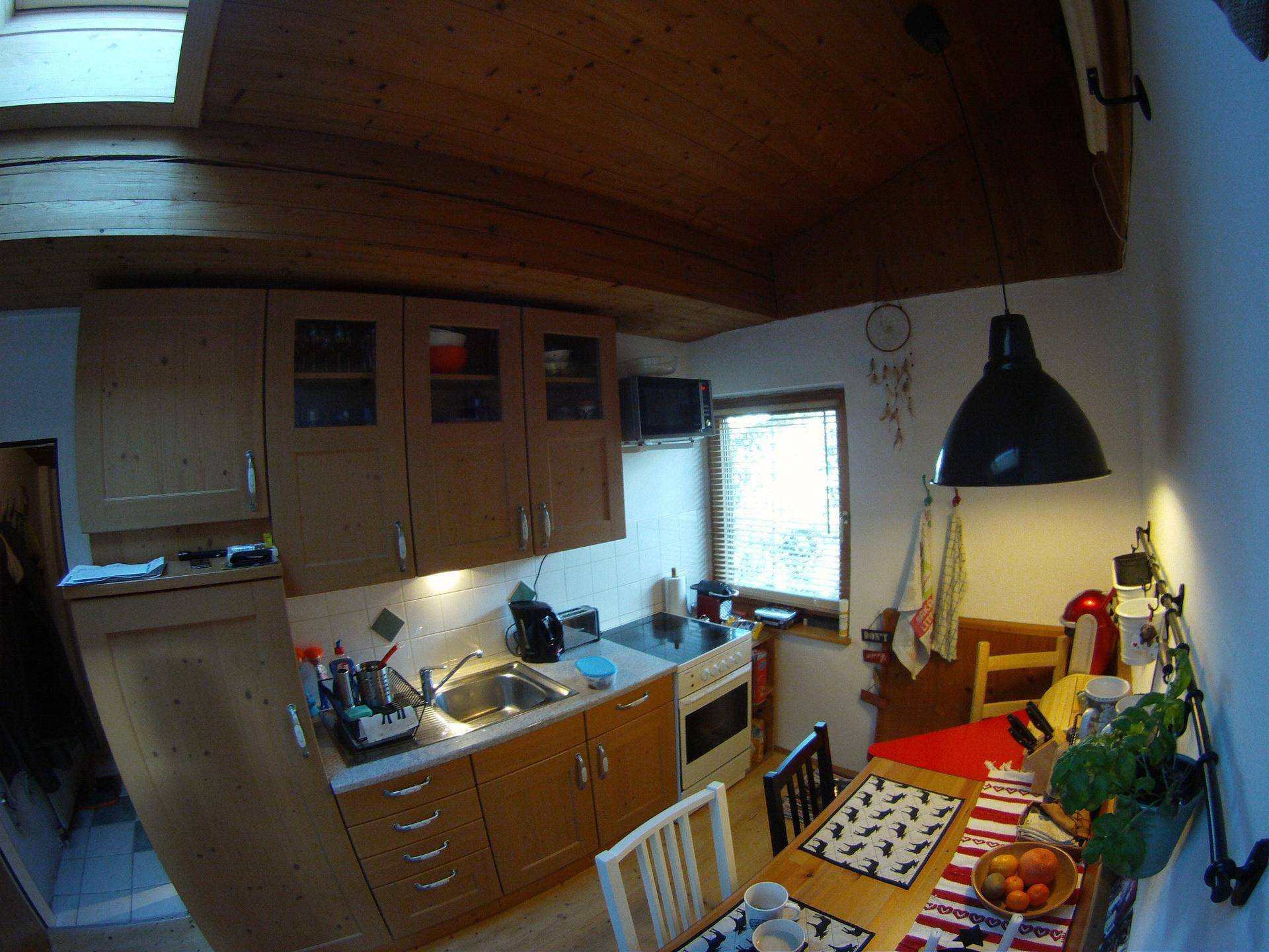 Küche mit Holzschränken, Essbereich und Dachfenster, das den Raum hell erleuchtet.