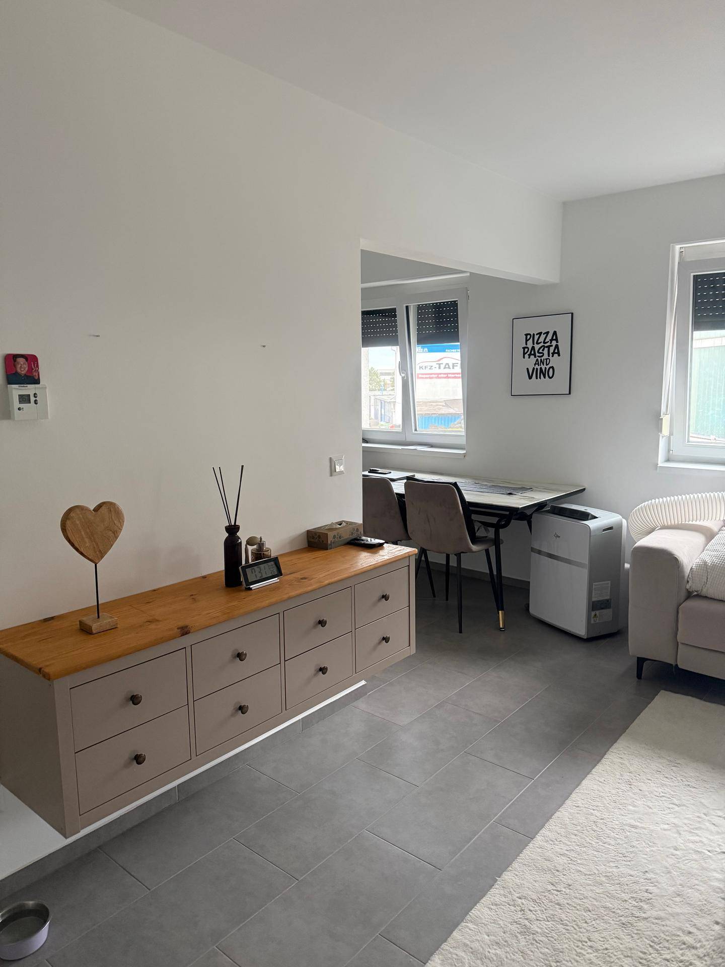 Offener Wohn- und Essbereich mit modernem Sideboard und Fliesenboden, hell und geräumig.
