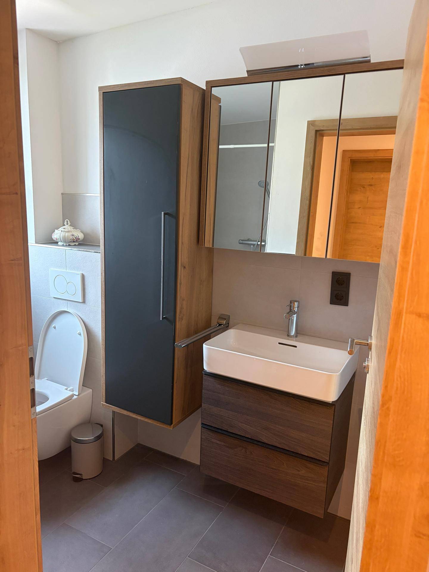 Modernes Badezimmer mit Einzelwaschbecken, Spiegelschrank und wandhängendem WC, in neutralen Farbtönen gehalten.
