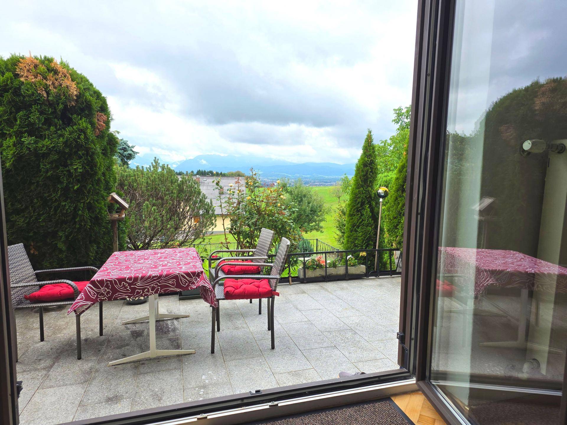 Gemütliche Terrasse mit Sitzgelegenheiten, zugänglich durch eine große Glastür, mit Landschafts- und Bergblick.