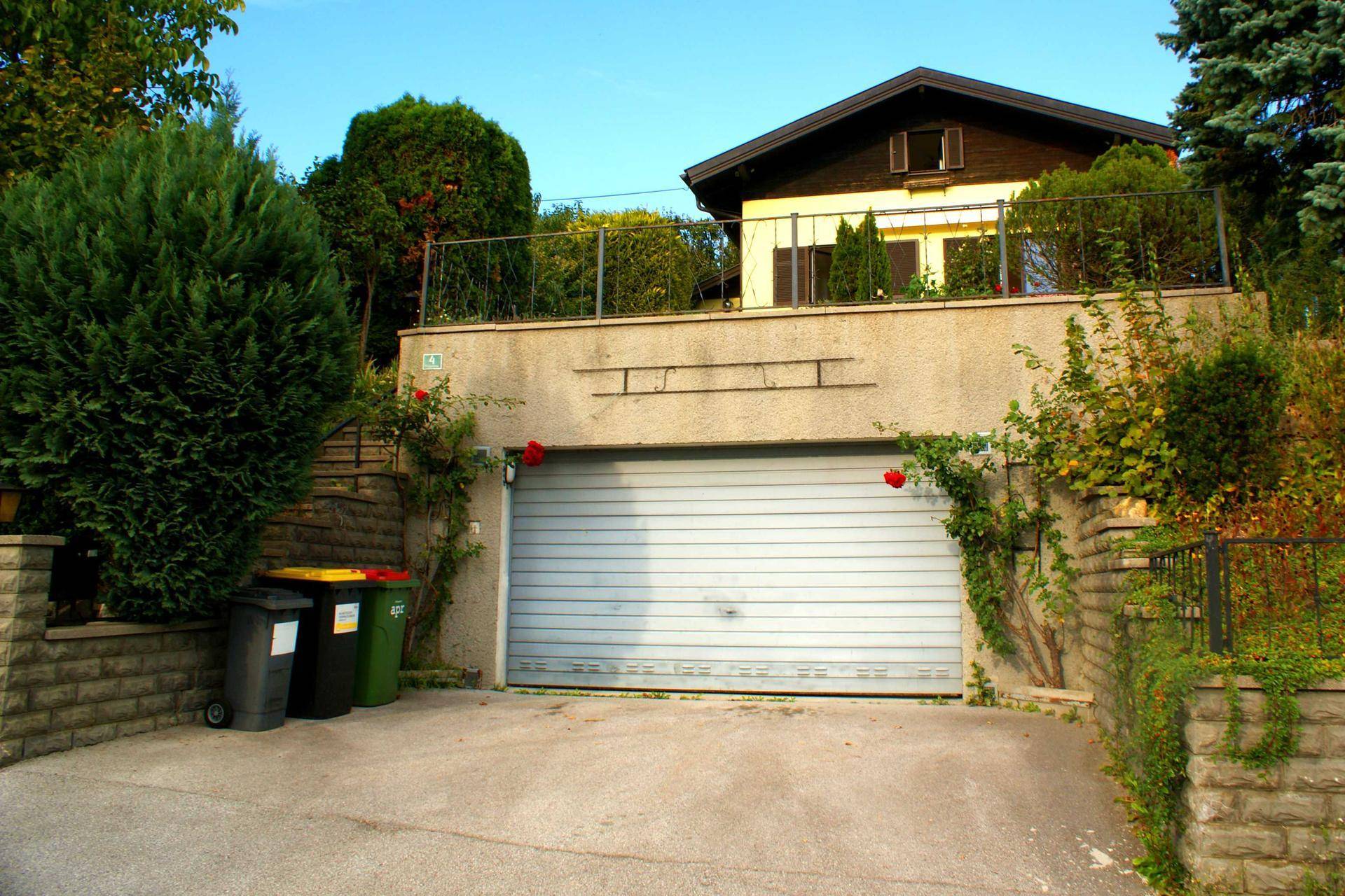 Einfahrt zur Garage im Untergeschoss des Hauses, umgeben von grüner Bepflanzung.