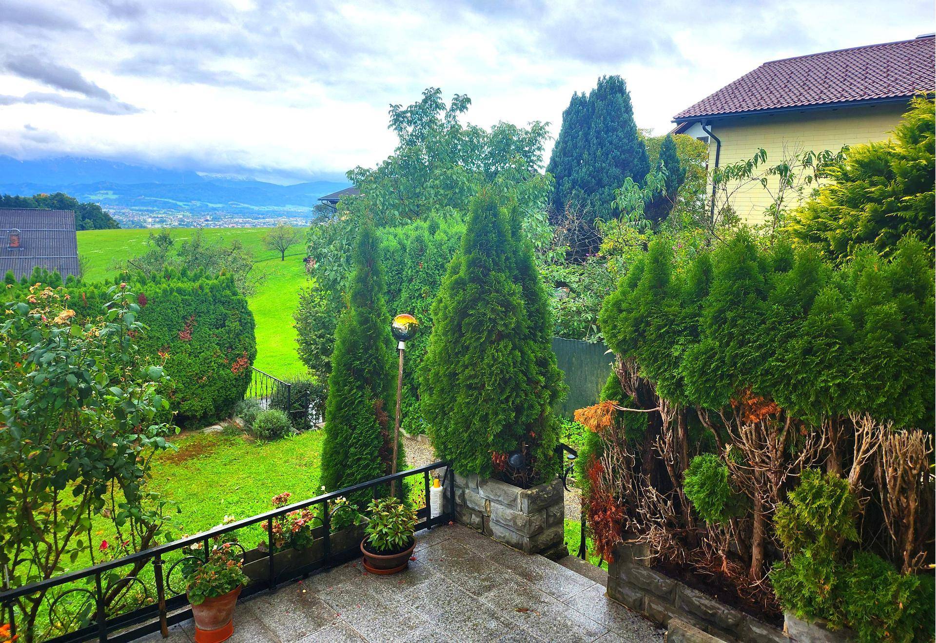 Geräumige Terrasse mit Blick auf die grüne Landschaft und die entfernte Stadt.