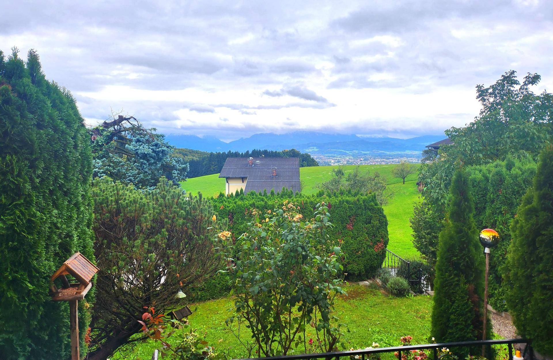Malerischer Garten mit üppigem Grün und weitem Blick auf die umliegende Landschaft und Berge.