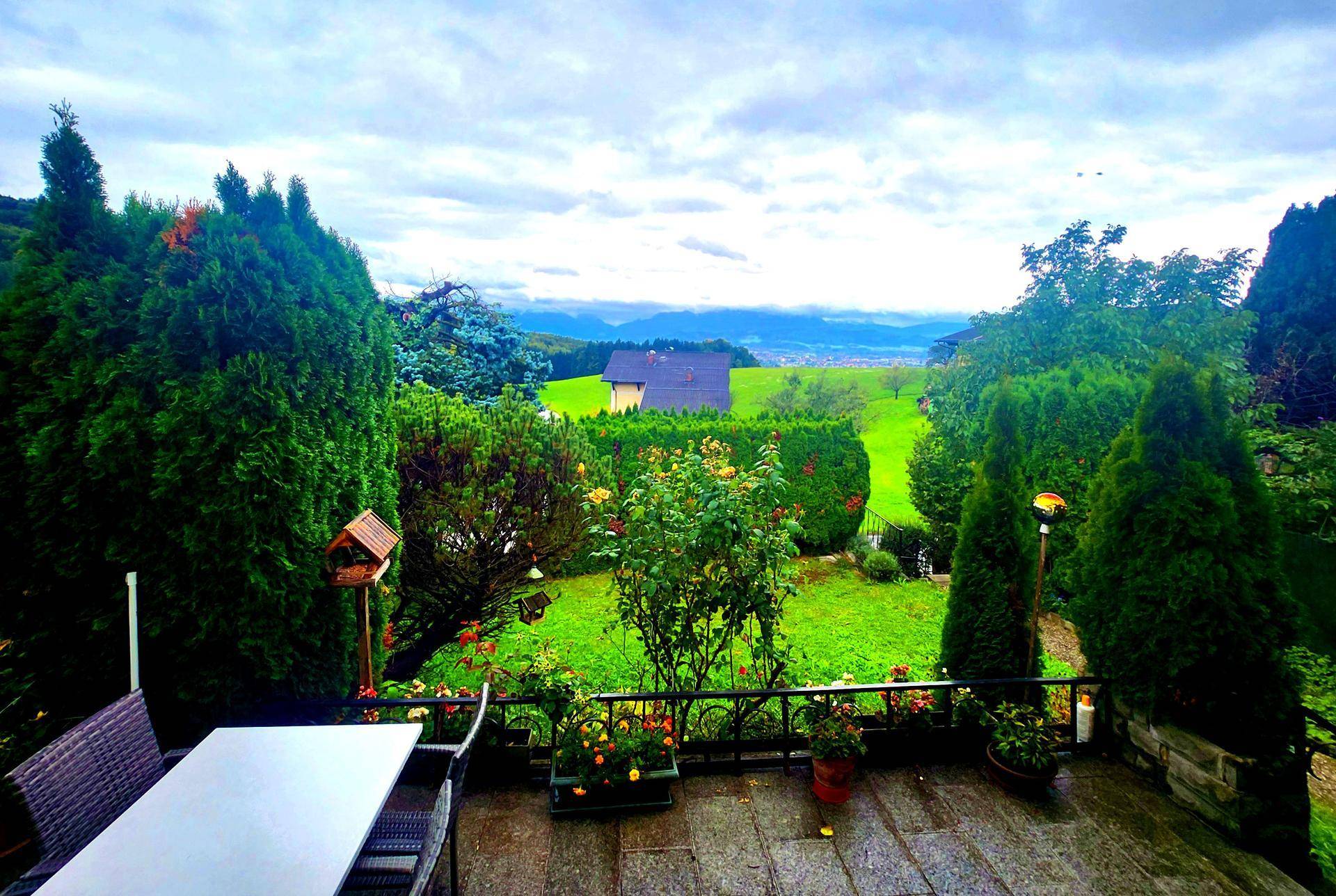 Geräumige Terrasse mit Esstisch und weitem Blick über grüne Hügel und die Landschaft.