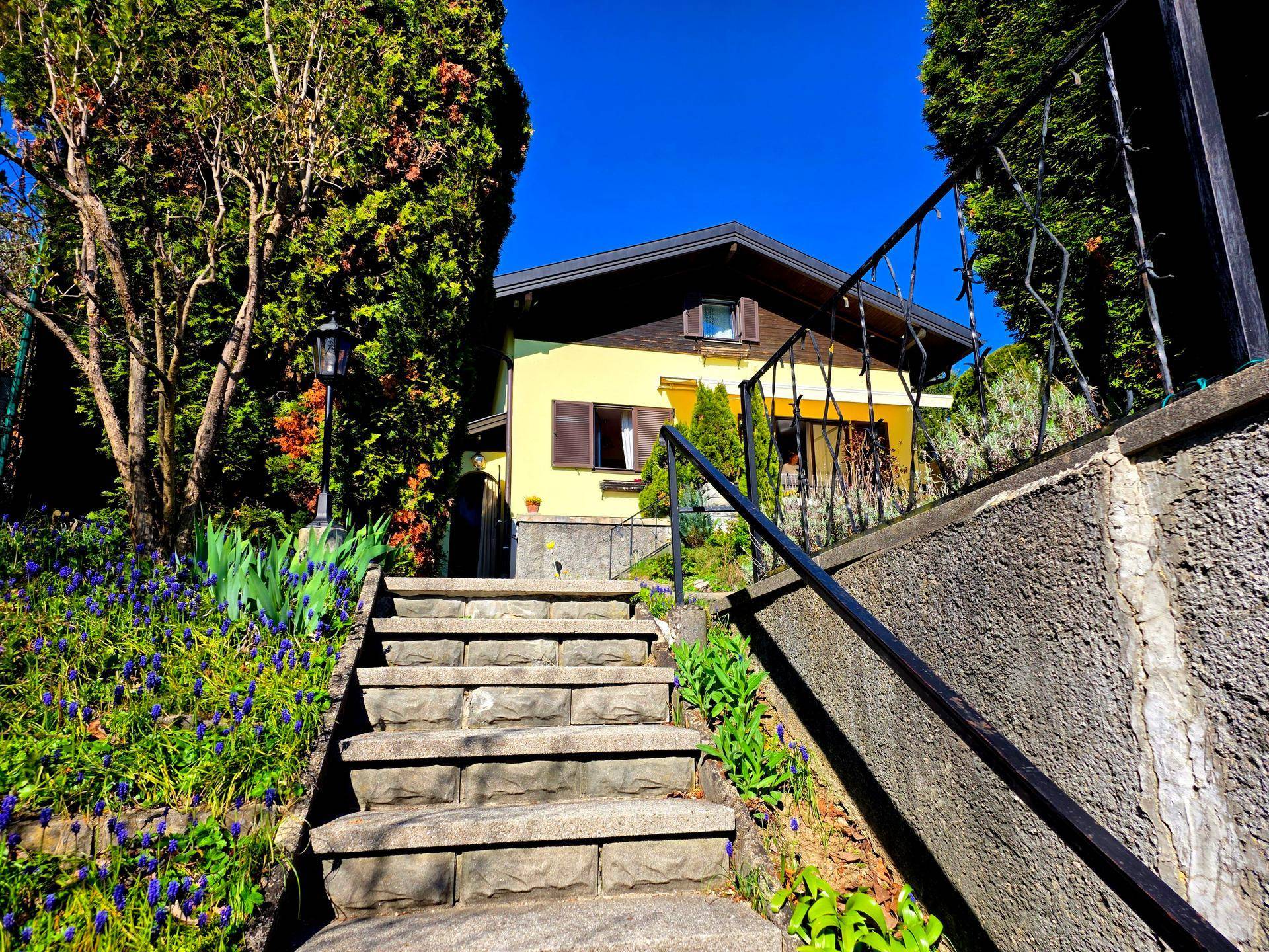 Steintreppe führt durch üppige Bepflanzung hinauf zum Eingang des Hauses.