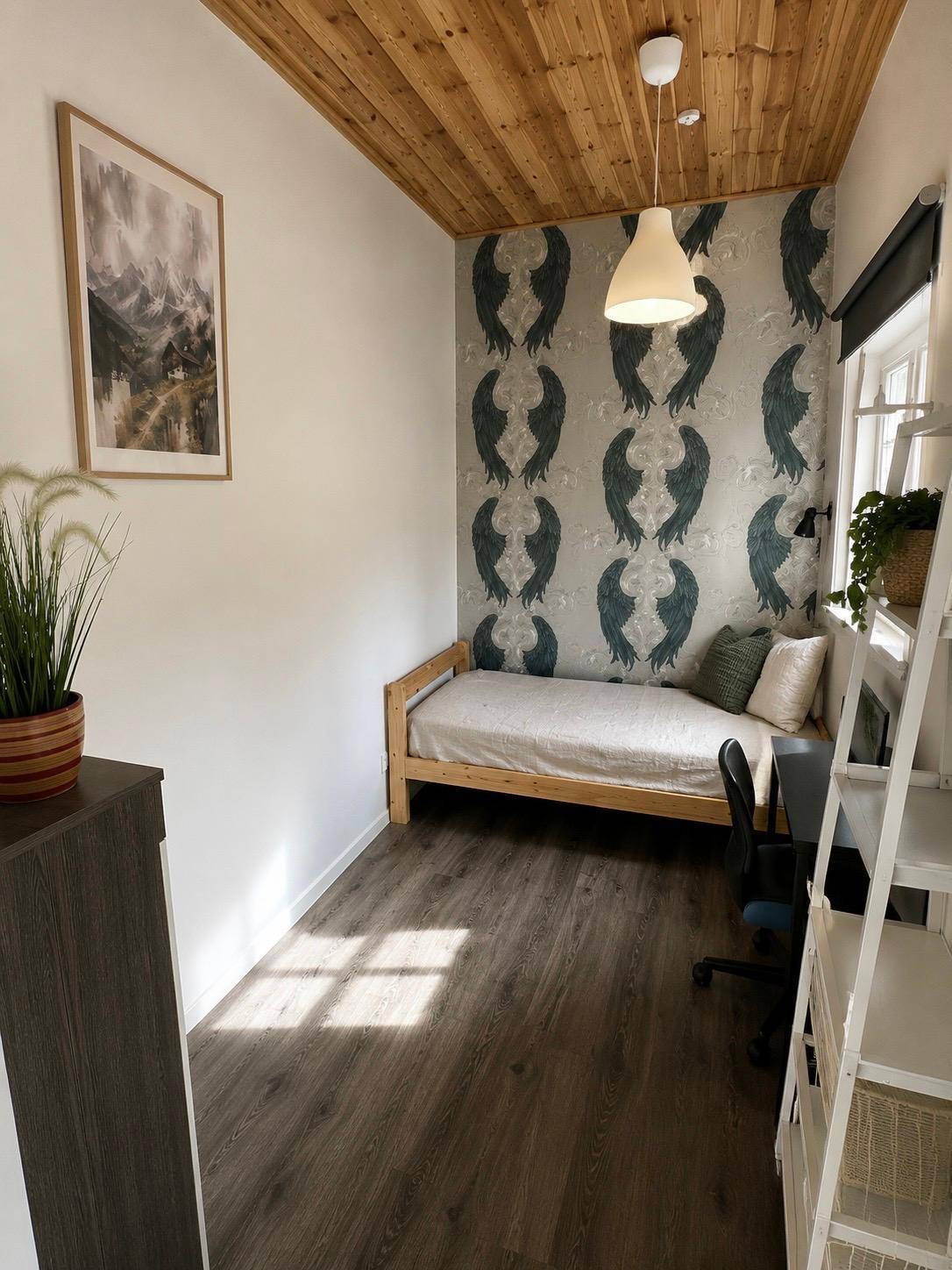 Kleines Schlafzimmer mit Einzelbett, Schreibtisch und dekorativer Tapete an einer Wand.