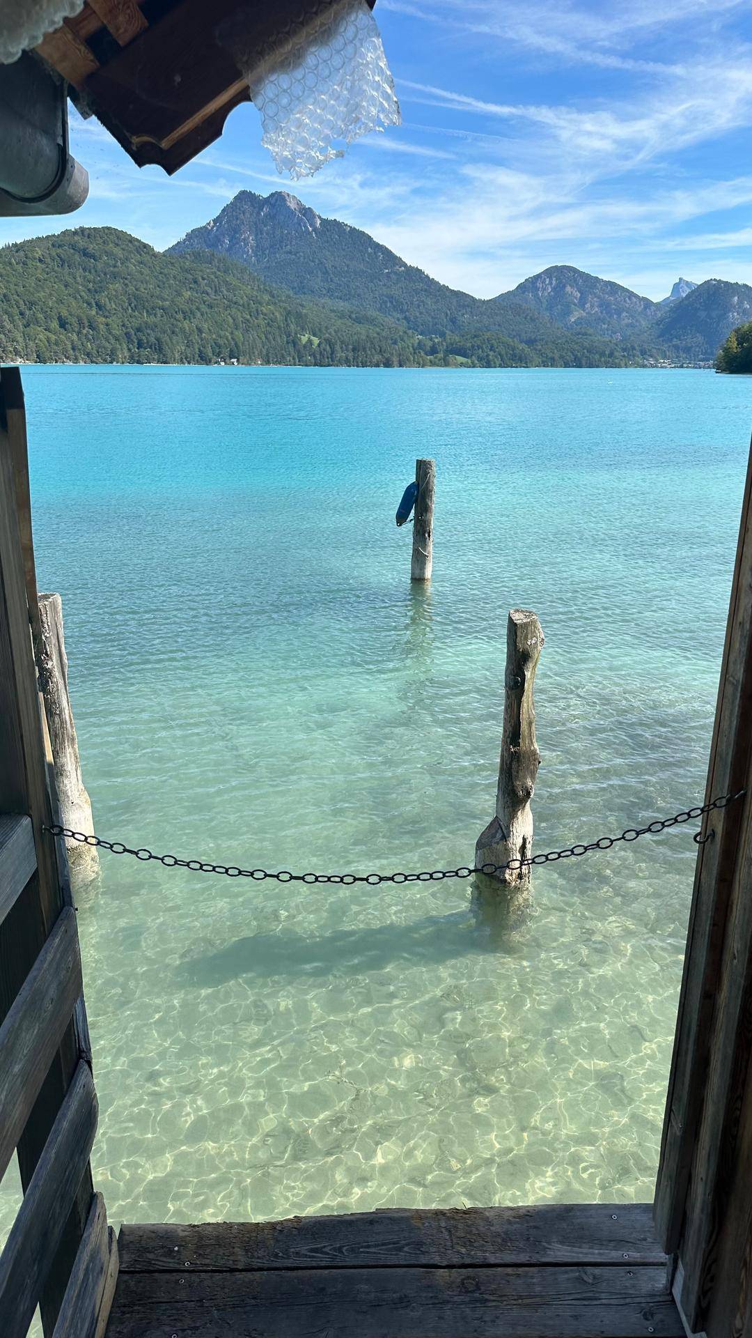 Malerischer Blick auf einen klaren türkisfarbenen See mit majestätischen Bergen im Hintergrund.