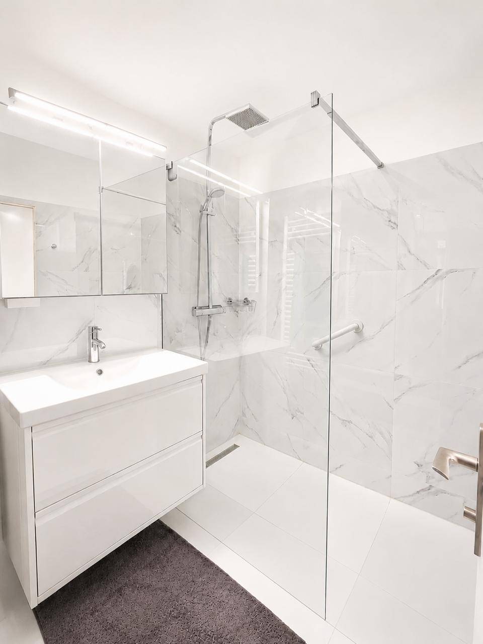 Elegantes Badezimmer mit großer Glasdusche, Waschtisch und Spiegelkabinett.
