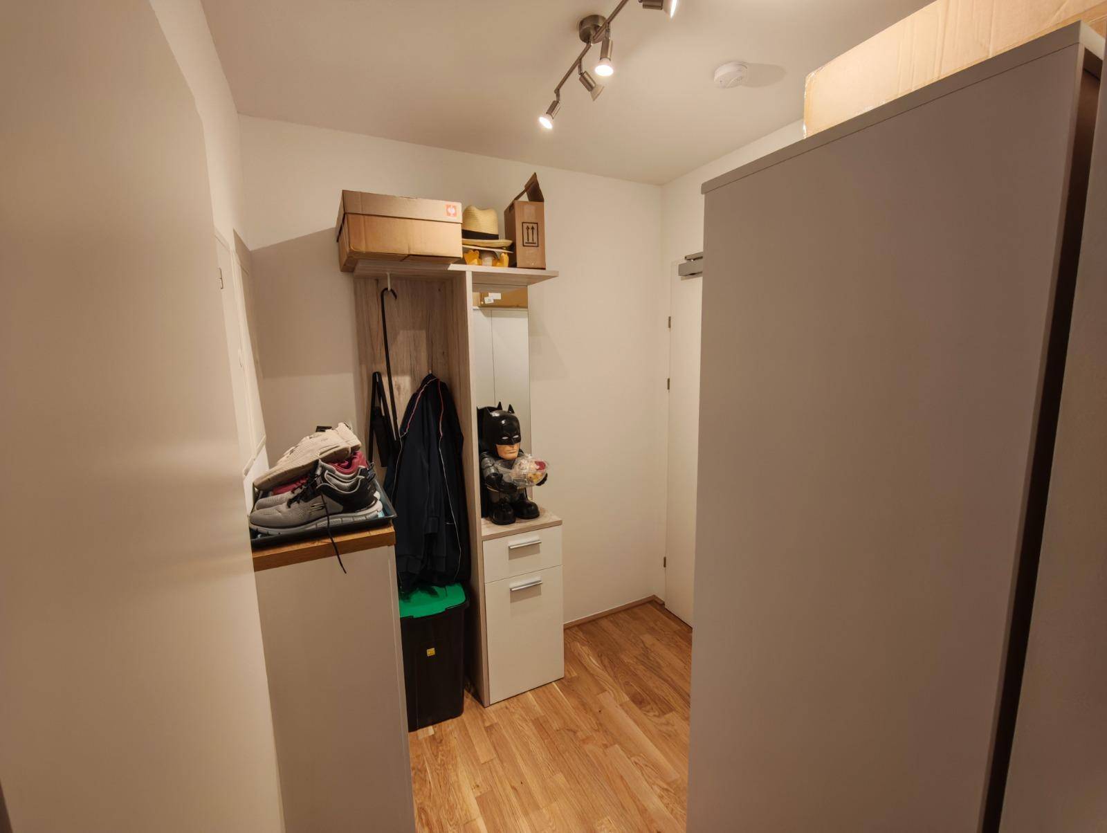 Heller Flur mit Garderobe, Spiegel und praktischen Aufbewahrungsmöbeln.