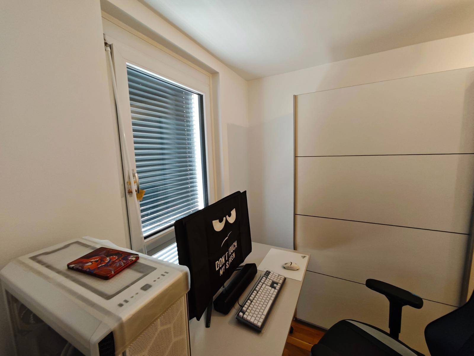 Helles Schlafzimmer mit Fenster, das viel Tageslicht hereinlässt, und einem Schreibtisch.