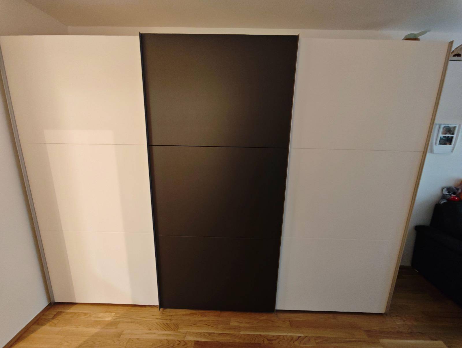 Großer, moderner Kleiderschrank mit weißen und schwarzen Schiebetüren.