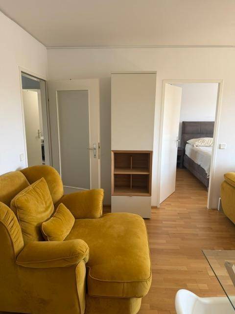 Blick vom Wohnzimmer in das Schlafzimmer, mit hellem Parkettboden und modernem Einbauschrank.
