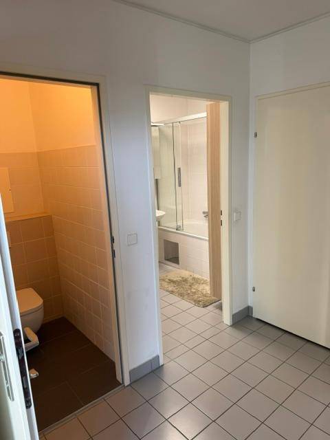 Flur mit Zugang zu separatem WC und Badezimmer, beide mit Fliesenboden.