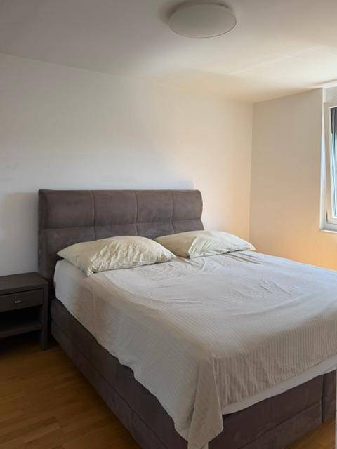 Helles Schlafzimmer mit großem Doppelbett, Nachttisch und schlichten weißen Wänden.