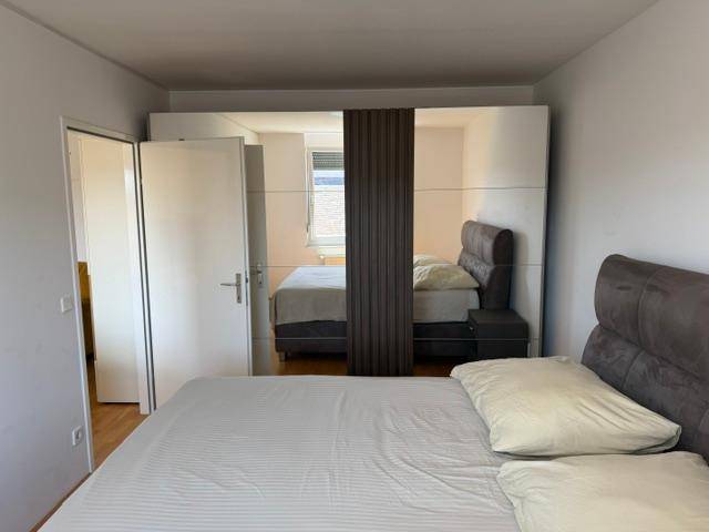 Schlafzimmer mit großem Bett und einem geräumigen Spiegelschrank, der den Raum optisch vergrößert.