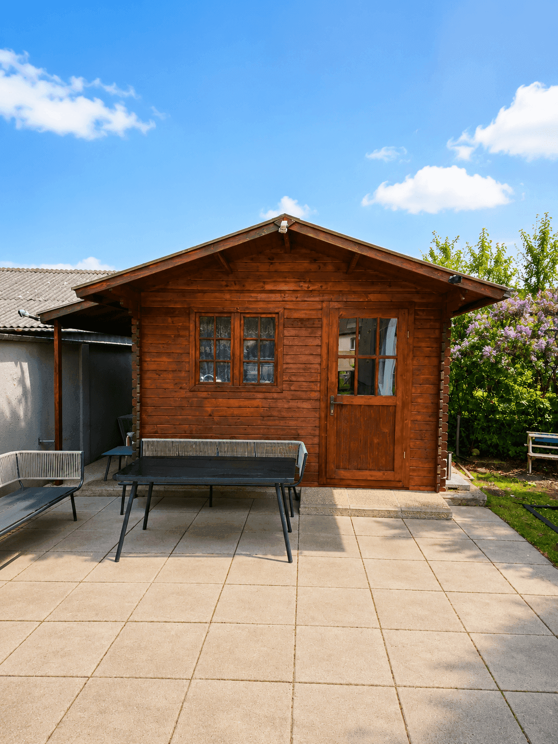 Gemütliche Terrasse mit Gartenmöbeln und einem hölzernen Gartenhaus im Grünen.