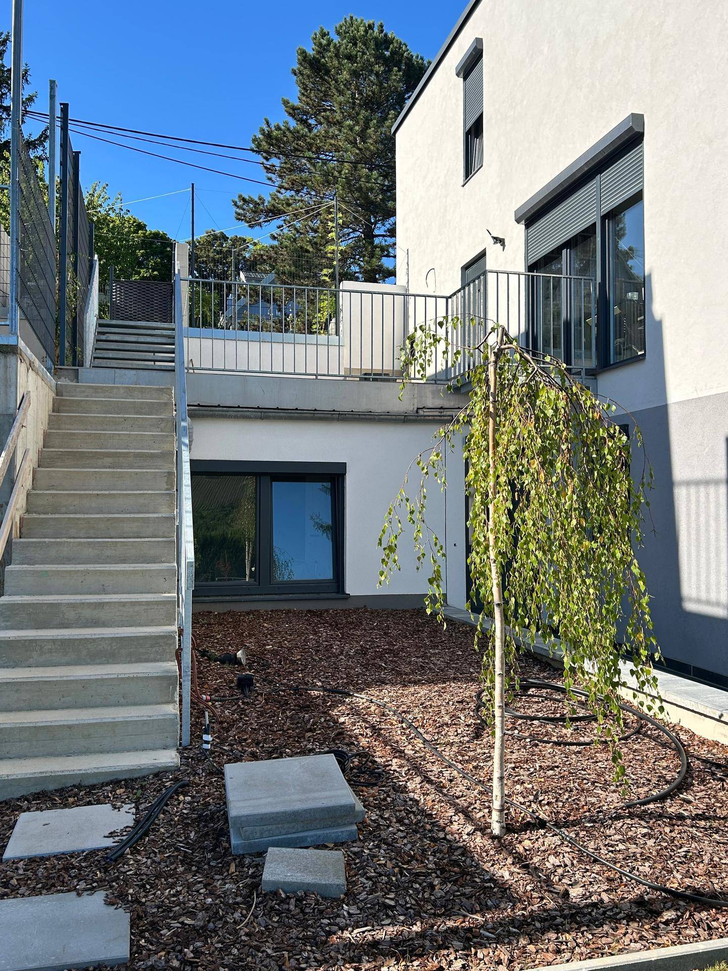 Außenansicht des Hauses mit Betontreppe, die zu einer oberen Ebene führt.