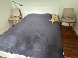 Schlafzimmer mit Doppelbett, dunkler Decke und zwei Stühlen als Nachttische.