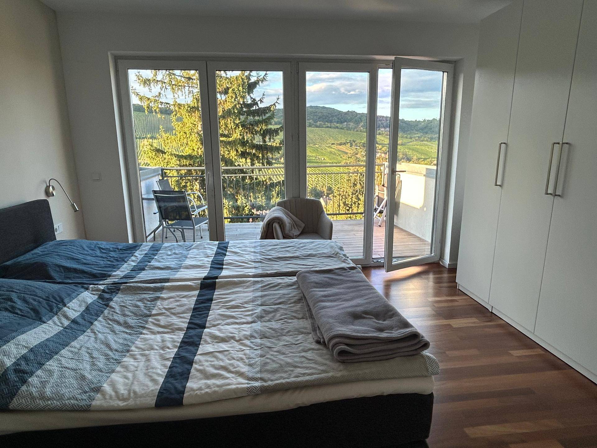 Schlafzimmer mit Doppelbett, Einbauschränken und Balkonzugang mit schöner Aussicht.