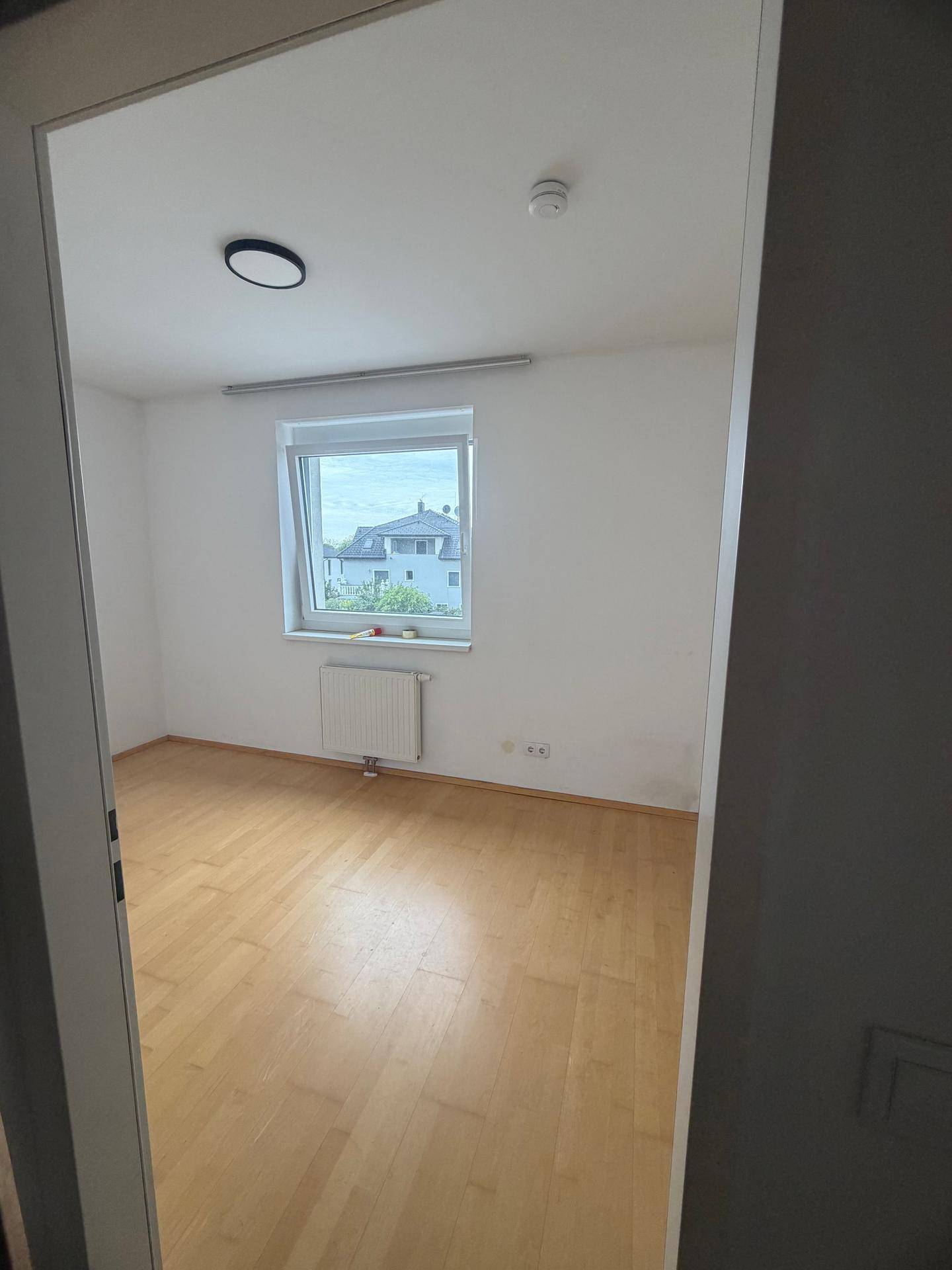 Weiteres helles Zimmer mit Parkettboden und Fenster, ideal als Schlaf- oder Arbeitszimmer.